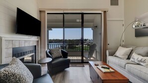 Una sala de estar moderna con chimenea, un sofá, una mesa de centro y un balcón con vistas a la ciudad.