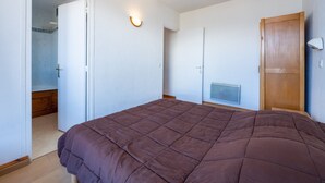 Ein Schlafzimmer mit einem großen Bett, einem Kleiderschrank, einer Tür zu einem Badezimmer und einem Wandheizkörper.