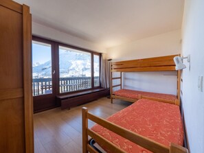 Una habitació amb dos llits superposats, una finestra gran amb vista a una muntanya nevada i un sòl de fusta.