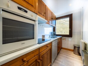 A kitchen with wooden cabinets, a built-in oven, a dishwasher, and a window providing a view of the outdoors. - Spacious apartment in Tignes, 9 guests, pets allowed, ski-in/out (Tignes)