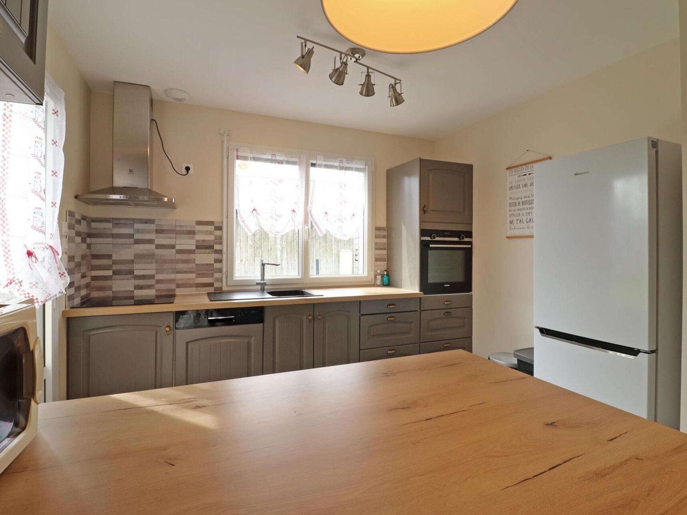 A modern kitchen with a wooden countertop, built-in oven, and a refrigerator.