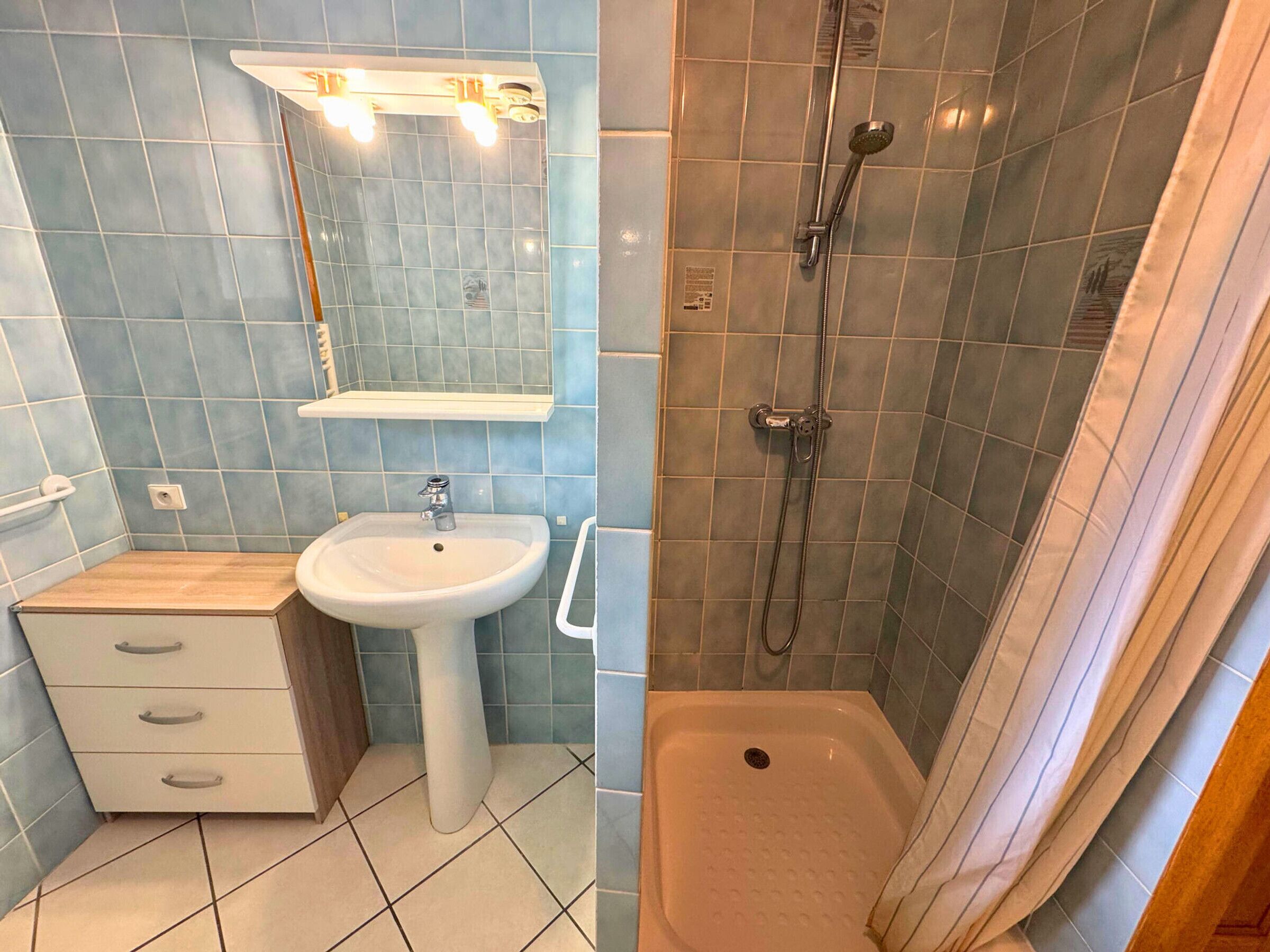 Une salle de bain avec un lavabo, un miroir et une douche.