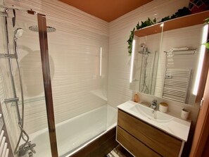 Bathroom features a glass-enclosed shower, sink, and vanity with a mirror.