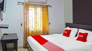 A hotel room with a bed, a bedside table, a TV, and an air conditioning unit. - Hotel O Abadi Hotel (Medan)