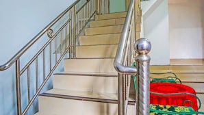 A staircase with metal railings and a red and green bag on the lower step. - Hotel O Abadi Hotel (Medan)