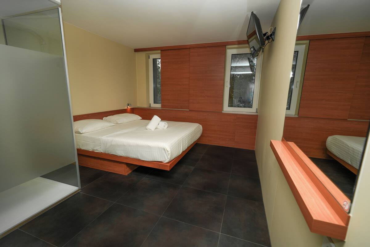Une chambre à coucher avec un lit, une petite fenêtre et un banc en bois.
