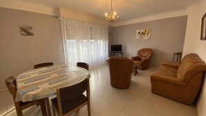 Un salon comprenant une table à manger, des chaises, un canapé et un téléviseur.