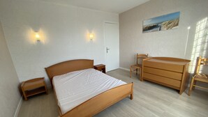 Une chambre à coucher avec un lit en bois, une commode, une chaise et deux tables de chevet.