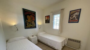 A bedroom with two single beds, a nightstand, a window with curtains, and two posters on the wall. - Apartment in Aiguablava with Pools and Wifi (Begur)