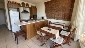 A compact kitchen with a central island, wooden chairs, and a dining table. - Apartment in Aiguablava with Pools and Wifi (Begur)