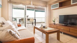 Un salón moderno con sofá, mesa de centro y televisor. Cuenta con un balcón y vistas.
