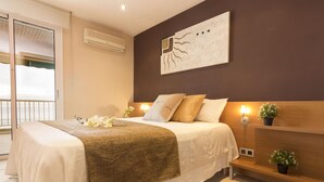 Un dormitorio con cama, mesita de noche, decoración en la pared y vistas a través de una puerta corredera.
