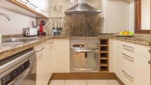 Una cocina moderna con horno empotrado, extractor de acero inoxidable y encimera de granito.