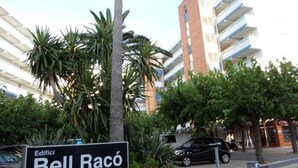 Señal para 'Edifici Bell Racó' con un edificio moderno al fondo.
