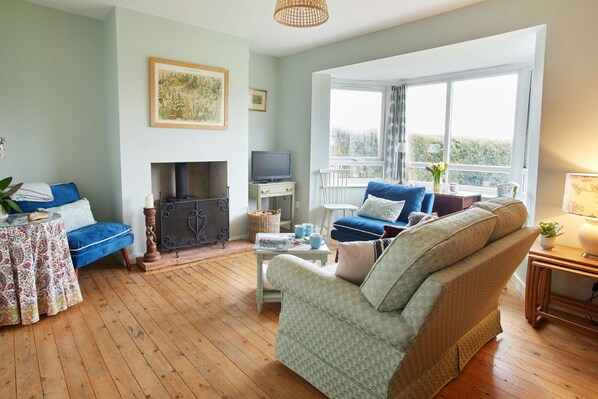 A cozy living room with a fireplace, a sofa, a television, and a large window with a view. - No 2 , Sparham Hall  - sleeps 5 guests  in 3 bedrooms (Swaffham)