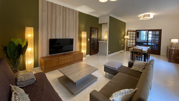 A modern living room with a flat-screen TV, a wooden entertainment unit, a coffee table, and a sofa.