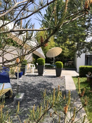 Eine Terrasse mit Sitzgelegenheiten im Freien, Kübelpflanzen und einem Weg zu einem Gebäude.