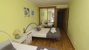 Habitación de hotel con dos camas, una mesita de noche con lámpara, un espejo y una obra de arte en la pared.