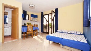 Une chambre à coucher avec un lit, un bureau et une chaise. Il y a une salle de bain avec un lavabo et un miroir.