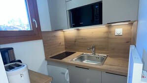 A compact kitchen with a microwave, sink, and a coffee maker.