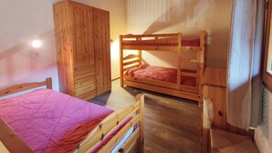 A bunk bed room with a wooden wardrobe and a single bed.