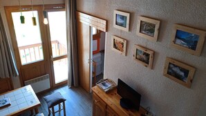 A cozy room with a wooden table, a TV, and a wall adorned with framed pictures.
