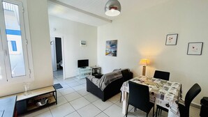 Un salon moderne comprenant un canapé, un téléviseur, une table à manger avec des chaises et une lampe.