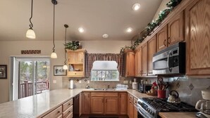 A kitchen with wooden cabinets, a stainless steel stove, and a large window.