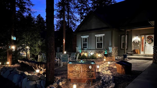 A house with a stone exterior, a front porch with chairs, and a wooden deck with a fire pit.