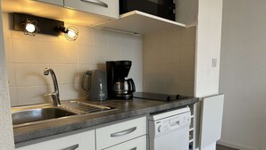 Une cuisine compacte équipée d’un évier, d’une bouilloire, d’une machine à café et d’un lave-vaisselle.