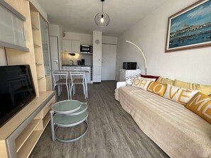 Um espaço compacto com cozinha compacta, área de jantar e sofá com almofadas decorativas.