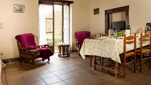 A dining area with a wooden table set for four, a small round table, and two armchairs. - 65 sqm cottage with fireplace, terrace, and children's play area (Saint-Médard-en-Forez)