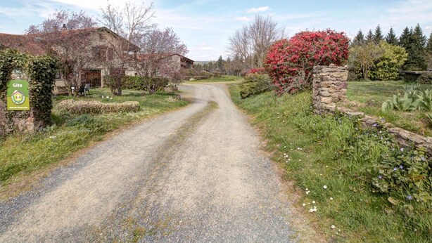 A rural road leading to a stone building with a sign indicating a Gîte. - 65 sqm cottage with fireplace, terrace, and children's play area (Saint-Médard-en-Forez)