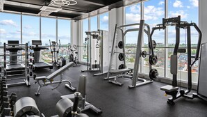 A gym with various exercise equipment, large windows, and a city view. - MLZ APARTMENTS (Sihanoukville)