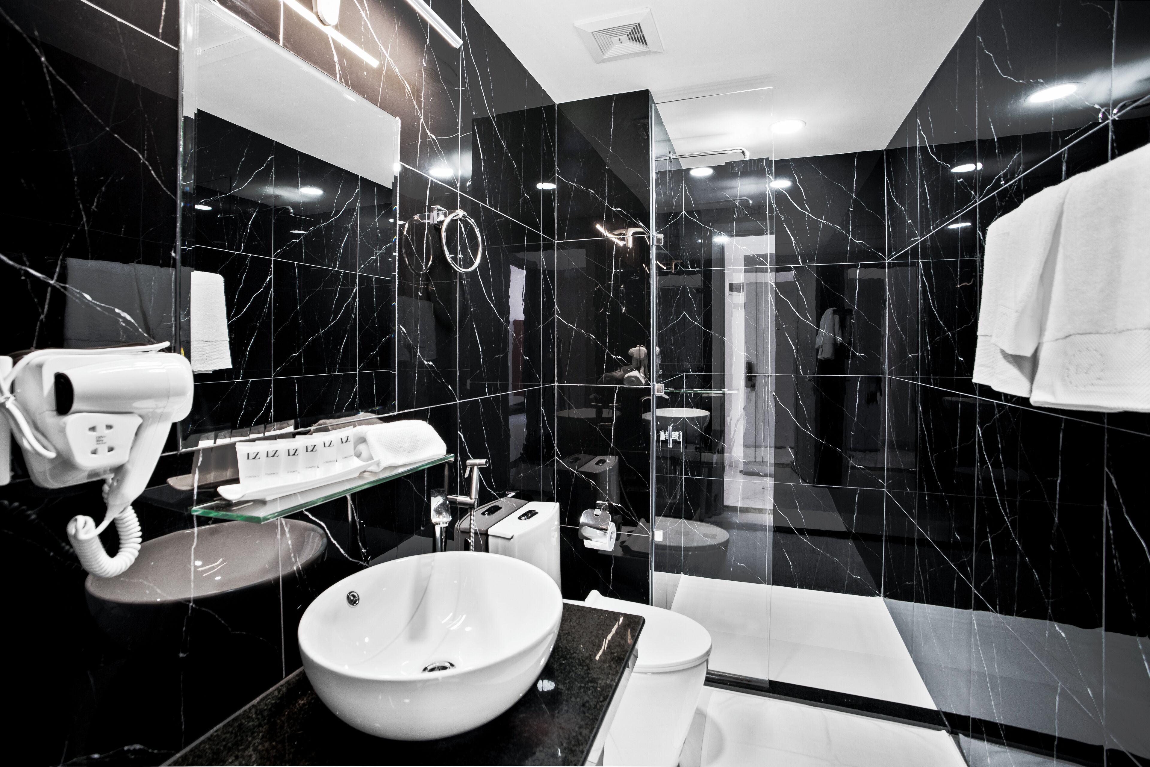 A modern bathroom with a large mirror, a sink, a toilet, and a shower area.