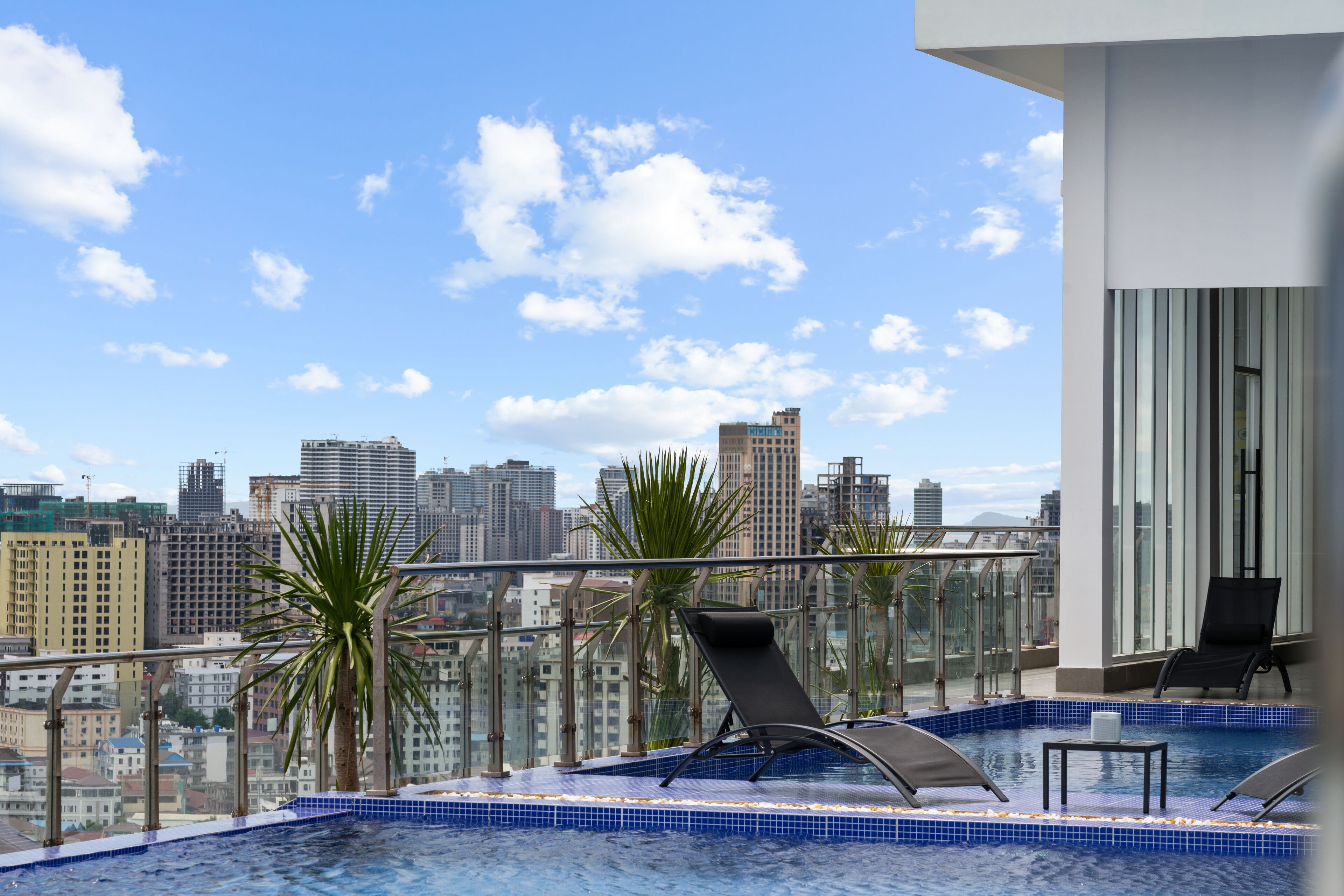 A rooftop pool with lounge chairs and a city view.