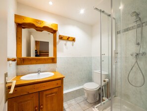 A bathroom with a wooden vanity, a white sink, a mirror, a glass shower enclosure, and a toilet. - Spacious ski-in/ski-out apartment for 10 with balcony, pets allowed (Tignes)