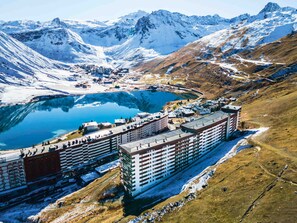 A hotel with multiple floors, located near a lake and mountains. - Spacious ski-in/ski-out apartment for 10 with balcony, pets allowed (Tignes)
