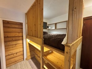 A bunk bed room with wooden walls and a single bed.
