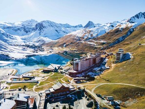 A mountainous landscape with a large body of water, a ski resort, and several buildings including a hotel. - Spacious ski-in/ski-out apartment for 10 with balcony, pets allowed (Tignes)