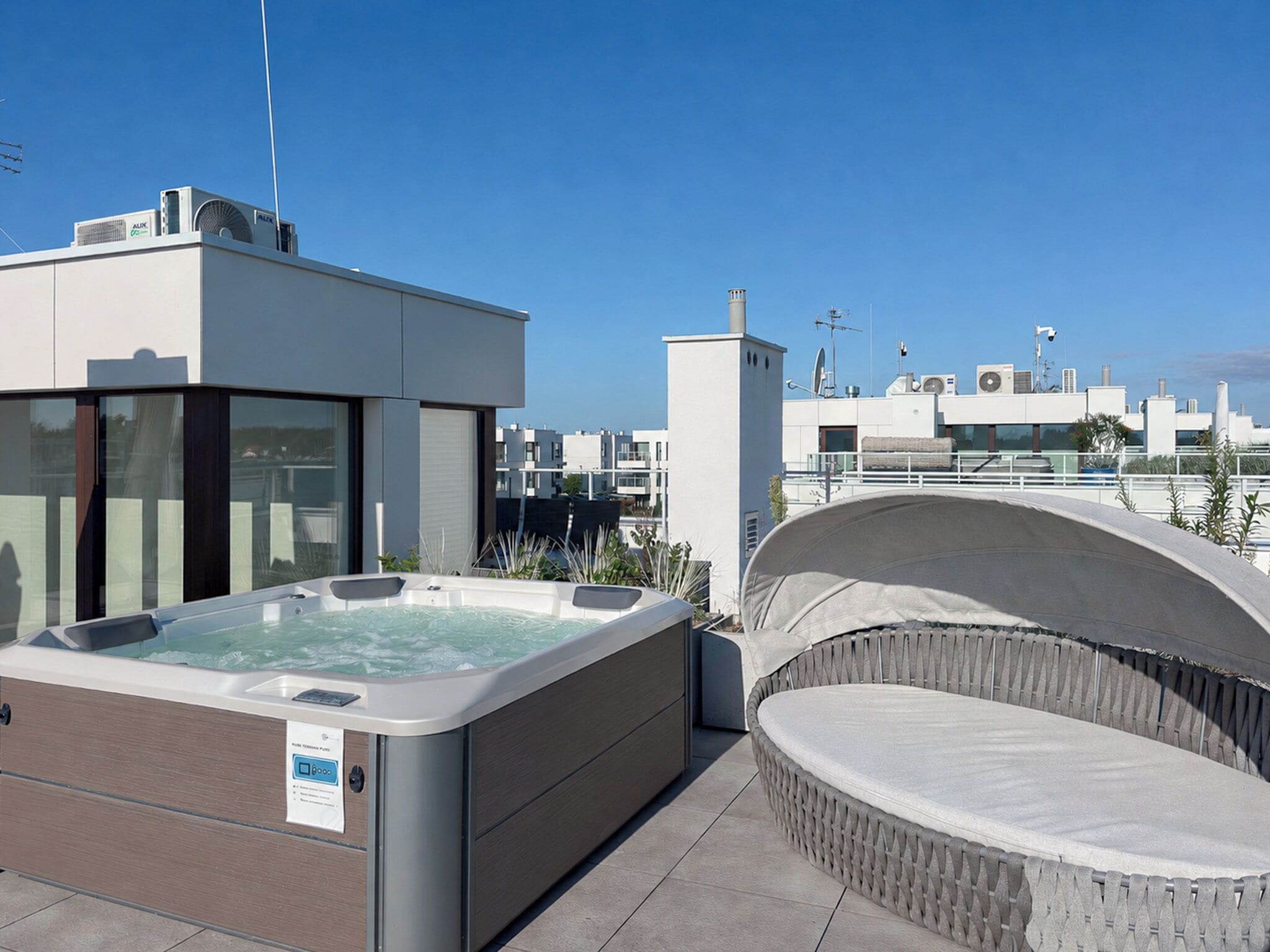 Una terraza con jacuzzi, un edificio moderno y cielo despejado.