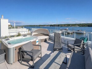 Une terrasse sur le toit avec un jacuzzi, des chaises longues et une vue sur la marina et le lac.
