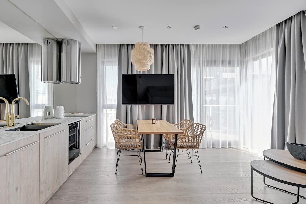 Una cocina moderna con comedor, televisor de pantalla plana y un amplio ventanal con cortinas.