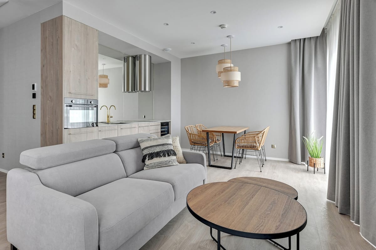 Una sala de estar moderna con un sofá, una mesa de comedor y una cocina al fondo.