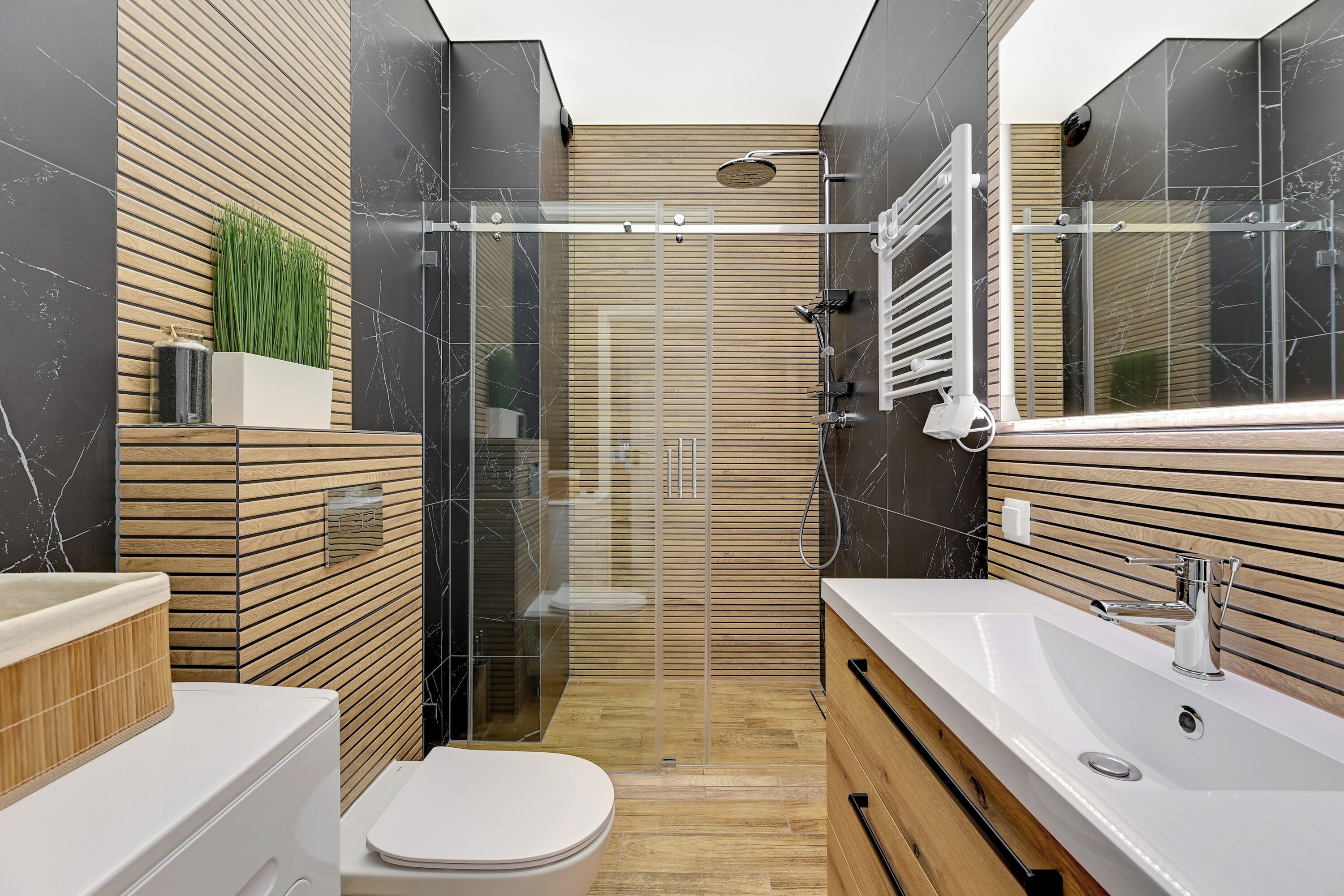 Un baño moderno con cabina de ducha acristalada, tocador de madera y váter blanco.