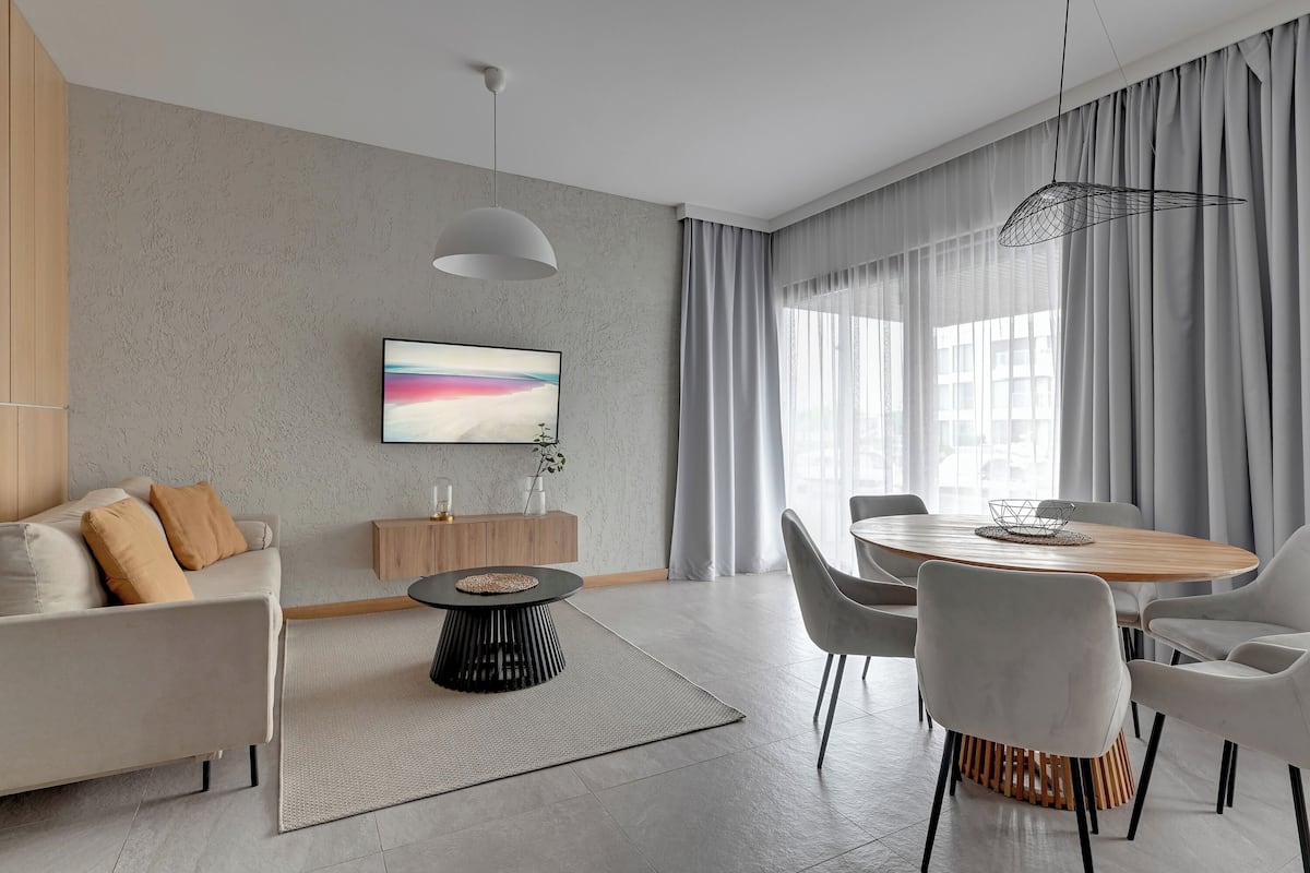 Una sala de estar moderna con un sofá, una mesa de comedor y un televisor.