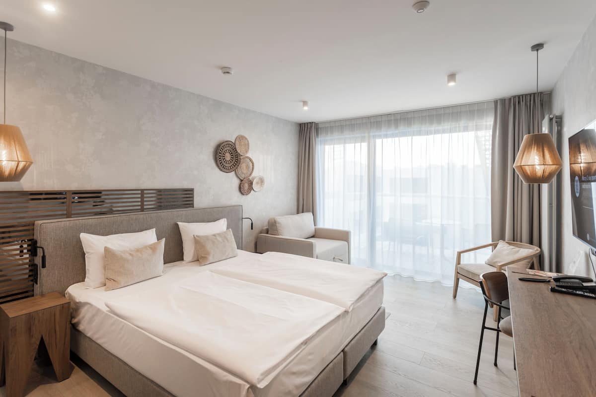 Una habitación de hotel moderna con una cama grande, un escritorio y una silla.
