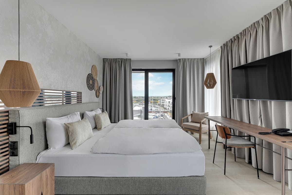 Una habitación de hotel moderna con una cama grande, un escritorio, una silla y un televisor.