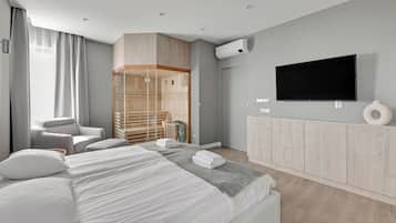 Una habitación de hotel moderna con una cama grande, televisor, armario y zona de estar.