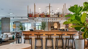 Een bar met krukken, een toog en verschillende flessen en glazen.